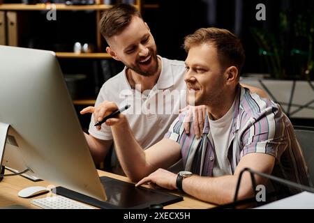 Due uomini felici ed eleganti che lavorano insieme in un ufficio moderno, concentrati sullo schermo di un computer. Foto Stock