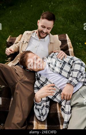 Due uomini in abiti casual sdraiati su una coperta all'aperto. Foto Stock