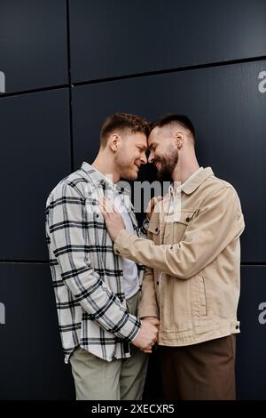 Due uomini in un abbigliamento casual in piedi davanti a un muro nero. Foto Stock