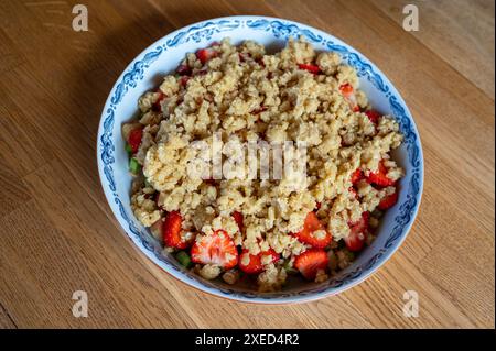 Sbriciolare l'impasto su pezzi di fragola e rabarbaro Foto Stock