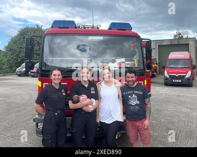 Foto di Alice Hearle e Josh Beardmore con la loro bambina Olive, nata nel retro di un'auto alle 14:36 del 16 maggio, riuniti con i vigili del fuoco Rosie Tonkin (a sinistra) e Katie Hoskins del Cornwall Fire and Rescue Service che hanno contribuito a portare Olivia nel mondo. Data di pubblicazione: Giovedì 27 giugno 2024. Foto Stock