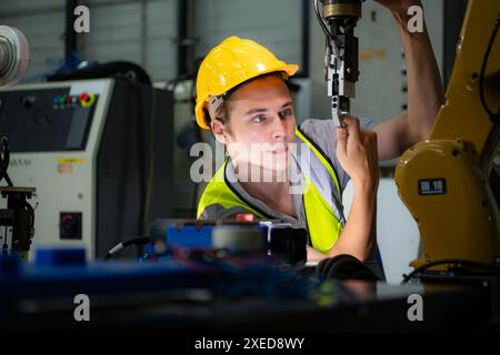 Tecnico che gestisce un piccolo braccio robot il funzionamento di un piccolo braccio robot utilizzato nell'industria è in fase di riparazione. Foto Stock