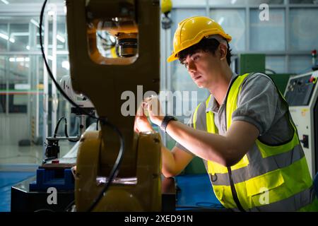 Tecnico che gestisce un piccolo braccio robot il funzionamento di un piccolo braccio robot utilizzato nell'industria è in fase di riparazione. Foto Stock