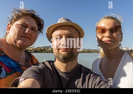 Questa immagine cattura un momento di amicizia. Un uomo, in piedi al centro, è affiancato da due donne bionde. Foto Stock