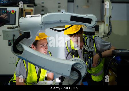 Tecnico che gestisce un piccolo braccio robot il funzionamento di un piccolo braccio robot utilizzato nell'industria è in fase di riparazione. Foto Stock