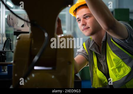 Tecnico che gestisce un piccolo braccio robot il funzionamento di un piccolo braccio robot utilizzato nell'industria è in fase di riparazione. Foto Stock