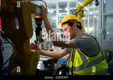 Tecnico che gestisce un piccolo braccio robot il funzionamento di un piccolo braccio robot utilizzato nell'industria è in fase di riparazione. Foto Stock