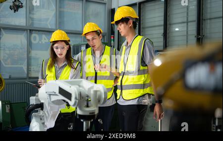 Ingegnere e tecnico che discutono del braccio robotico in fabbrica circa il funzionamento, la manutenzione e la riparazione del lavoro Foto Stock