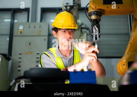 Tecnico che gestisce un piccolo braccio robot il funzionamento di un piccolo braccio robot utilizzato nell'industria è in fase di riparazione. Foto Stock