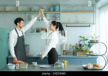 Un marito indossa un grembiule mentre cucina la cena con sua moglie. Stava ballando felicemente prima di entrare in cucina per cucinare. Foto Stock