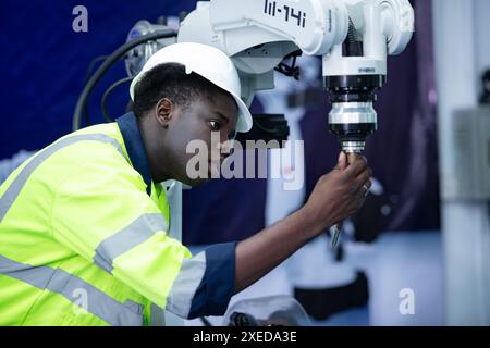 Tecnico che gestisce un piccolo braccio robot il funzionamento di un piccolo braccio robot utilizzato nell'industria è in fase di riparazione. Foto Stock