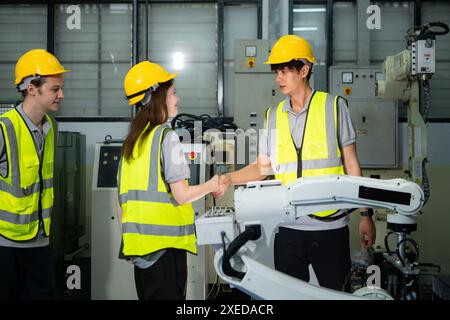 Ingegnere e lavoratore che stringono la mano mentre lavora su macchine industriali in fabbrica Foto Stock