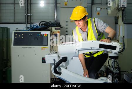 Tecnico che gestisce un piccolo braccio robot il funzionamento di un piccolo braccio robot utilizzato nell'industria è in fase di riparazione. Foto Stock