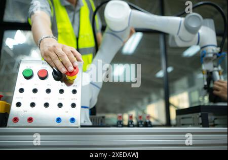 Primo piano della mano premendo il pulsante STOP sul pannello di controllo di una macchina industriale. Foto Stock