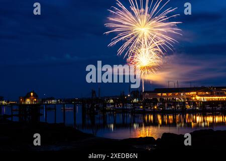 Boothbay Harbor, Stati Uniti. 26 giugno 2024. I fuochi d'artificio esplodono nel cielo sopra il porto e lo storico lungomare durante l'annuale festival Windjammer Days, 26 giugno 2024, a Boothbay Harbor, Maine. Windjammer Days, iniziato nel 1962, inizia la stagione estiva nella regione costiera. Crediti: Richard Ellis/Richard Ellis/Alamy Live News Foto Stock