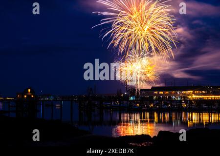 Boothbay Harbor, Stati Uniti. 26 giugno 2024. I fuochi d'artificio esplodono nel cielo sopra il porto e lo storico lungomare durante l'annuale festival Windjammer Days, 26 giugno 2024, a Boothbay Harbor, Maine. Windjammer Days, iniziato nel 1962, inizia la stagione estiva nella regione costiera. Crediti: Richard Ellis/Richard Ellis/Alamy Live News Foto Stock