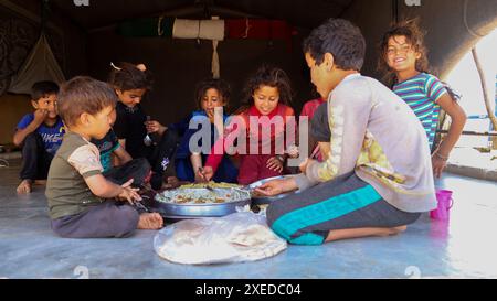 Sarmada, Governatorato di Idlib, Siria. 11 giugno 2024. Sarmada, Idlib, Siria. 11 giugno 2024. I bambini siriani sfollati mangiano in una tenda nel campo di Tell al-Fakhar nel nord-ovest della Siria. Tell al-Fakhar è uno dei campi di sfollati interni (IDP) vicino a Sarmada, nel governatorato di Idlib. I residenti del campo di Tell al-Fakhar vivono in tende usurate per 6 anni dopo essere stati sfollati dalle loro case a seguito di scioperi effettuati dalle forze governative siriane (immagine di credito: © Hussein Ali/IMAGESLIVE via ZUMA Press Wire) SOLO PER USO EDITORIALE! Non per USO commerciale! Foto Stock