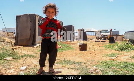 Sarmada, Governatorato di Idlib, Siria. 11 giugno 2024. Sarmada, Idlib, Siria. 11 giugno 2024. Un bambino siriano sfollato fuori da una tenda nel campo di Tell al-Fakhar nel nord-ovest della Siria. Tell al-Fakhar è uno dei campi di sfollati interni (IDP) vicino a Sarmada, nel governatorato di Idlib. I residenti del campo di Tell al-Fakhar vivono in tende usurate per 6 anni dopo essere stati sfollati dalle loro case a seguito di scioperi effettuati dalle forze governative siriane (immagine di credito: © Hussein Ali/IMAGESLIVE via ZUMA Press Wire) SOLO PER USO EDITORIALE! Non per USO commerciale! Foto Stock