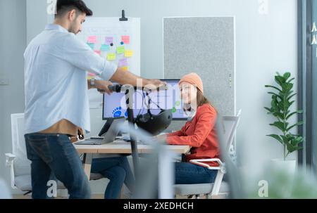 Uomo d'affari che guida uno scooter elettrico in ufficio con un collega in background Foto Stock