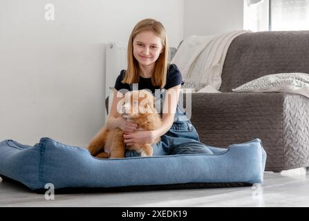 Piccola ragazza con cucciolo Toller siede nel Blue Dog Bed, Nova Scotia Duck Tolling Retriever Foto Stock