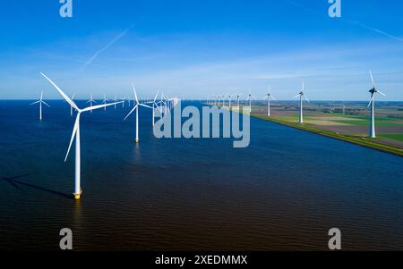 Un vasto bacino idrico nei Paesi Bassi Flevoland è costellato da numerosi mulini a vento torreggianti, Foto Stock