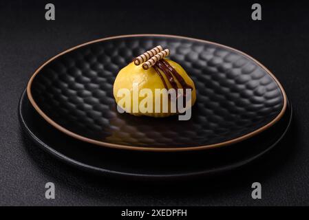 Deliziosi dolci e colorati dessert mochi o gelato con impasto di riso e condimenti su uno sfondo di cemento scuro Foto Stock