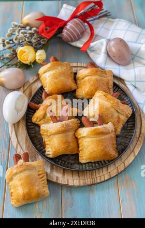 Panini sotto forma di coniglio pasquale e uova colorate su un tavolo di legno. Foto Stock