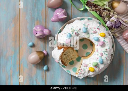 Torta al limone di pasqua glassata decorata con dolciumi e mini caramelle con uova di cioccolato su un tavolo di legno. Foto Stock
