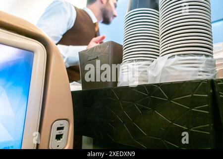 Assistente di volo che serve bevande ai passeggeri seduti su una sedia in una cabina di un aereo Boeing 787-10 Etihad Airways Foto Stock