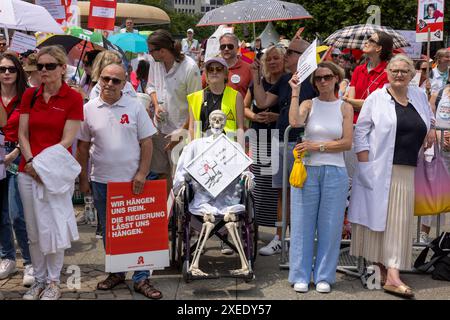 27 giugno 2024, Assia, Francoforte sul meno: I farmacisti protestano con uno scheletro su una sedia a rotelle contro i piani di riforma del governo federale in un raduno organizzato dall'Associazione dei farmacisti dell'Assia sull'Opernplatz a Francoforte. Foto: Helmut Fricke/dpa Foto Stock