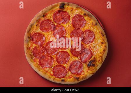 Pizza fresca e gustosa con peperoni su fondo rosso Foto Stock