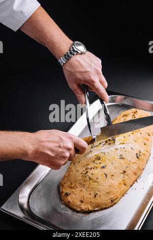 Pesce al forno, ripieno di erbe aromatiche, in crosta di sale tagliata dallo chef Foto Stock