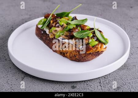 Toast con funghi porcini fritti su piatto bianco Foto Stock