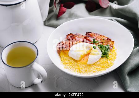 Pezzi di pancetta fritti e uova in camicia su un piatto Foto Stock