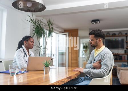 Giovane uomo visita donna medico in ufficio medici, avendo problemi di salute con dolore, parlare con il medico generico in cappotto bianco con stetoscopio a. Foto Stock