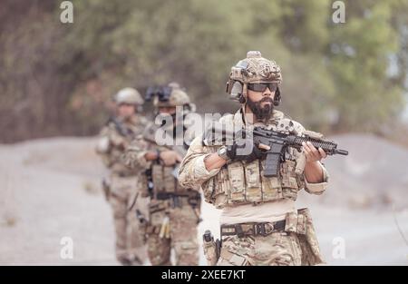 Soldati in uniformi militari mimetiche che trasportano armi, missioni di ricognizione in aspre montagne, battaglia di fanteria d'assalto Foto Stock