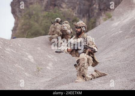 Soldati in uniformi militari mimetiche che trasportano armi, missioni di ricognizione in aspre montagne, battaglia di fanteria d'assalto Foto Stock