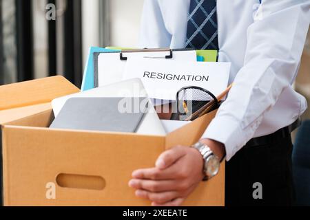 L'uomo mette oggetti personali e lettere di dimissioni in una scatola, ponendo fine al suo mandato. Foto Stock