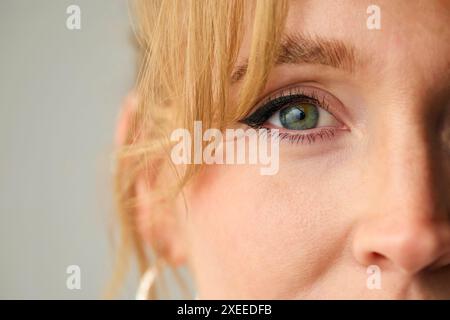 Primo piano dello Studio Shot of Woman's Eye Looking At camera su sfondo Plain Studio Foto Stock