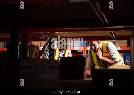 Un gruppo di dipendenti del magazzino che ispezionano i prodotti sugli scaffali del magazzino prima di essere inviati al rivenditore Foto Stock
