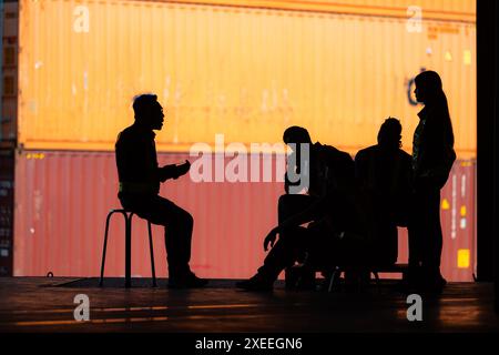 Gruppo di dipendenti del magazzino che parlano e si incontrano comodamente durante il lavoro, concetto silhouette. Foto Stock