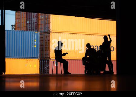 Gruppo di dipendenti del magazzino che parlano e si incontrano comodamente durante il lavoro, concetto silhouette. Foto Stock