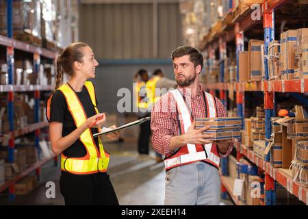 Un gruppo di dipendenti del magazzino che ispezionano i prodotti sugli scaffali del magazzino prima di essere inviati al rivenditore Foto Stock