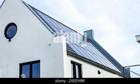 Case di nuova costruzione con pannelli solari attaccati sul tetto contro un cielo soleggiato Foto Stock