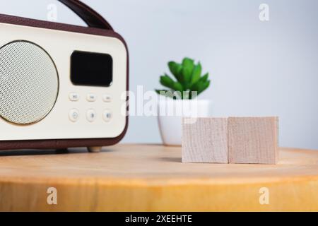 radio d'epoca e piccola pianta in vaso su un tavolo di legno con due blocchi di legno, routine mattutina e notizie Foto Stock