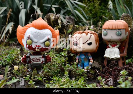 Figure Funko Pop tratte da film horror. Clown malvagio Pennywise, bambole spaventose Chucky e Annabelle. Moodia, cupa, spaventosa, foresta verde scura. Foto Stock