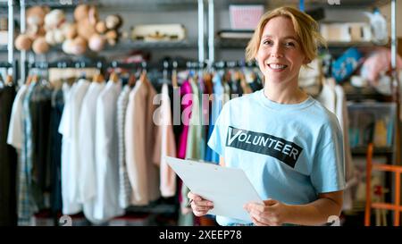 Ritratto del volontario di beneficenza femminile con appunti che lavora al negozio di abbigliamento Thrift Foto Stock