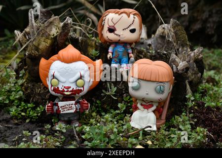 Figure Funko Pop tratte da film horror. Clown malvagio Pennywise, bambole spaventose Chucky e Annabelle. Moodia, cupa, spaventosa, foresta verde scura. Foto Stock