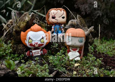 Figure Funko Pop tratte da film horror. Clown malvagio Pennywise, bambole spaventose Chucky e Annabelle. Moodia, cupa, spaventosa, foresta verde scura. Foto Stock