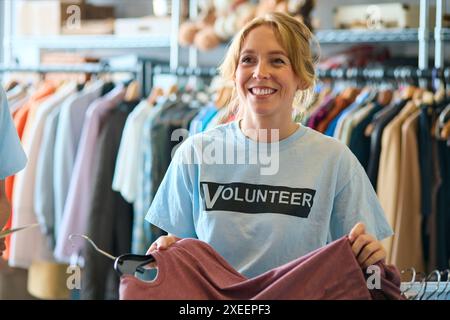 Lavoratrice di beneficenza che controlla le donazioni di abbigliamento al Thrift Store Foto Stock